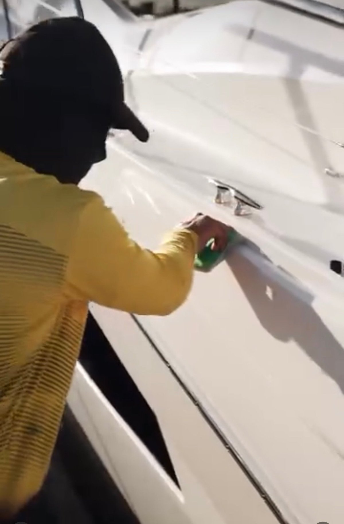 Technician in a yellow shirt and black cap opening a hatch door during a ceramic coating application on a yacht
